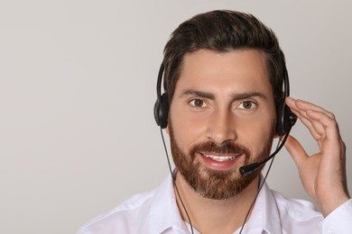 Photo of Hotline operator with headset on light grey background, space for text