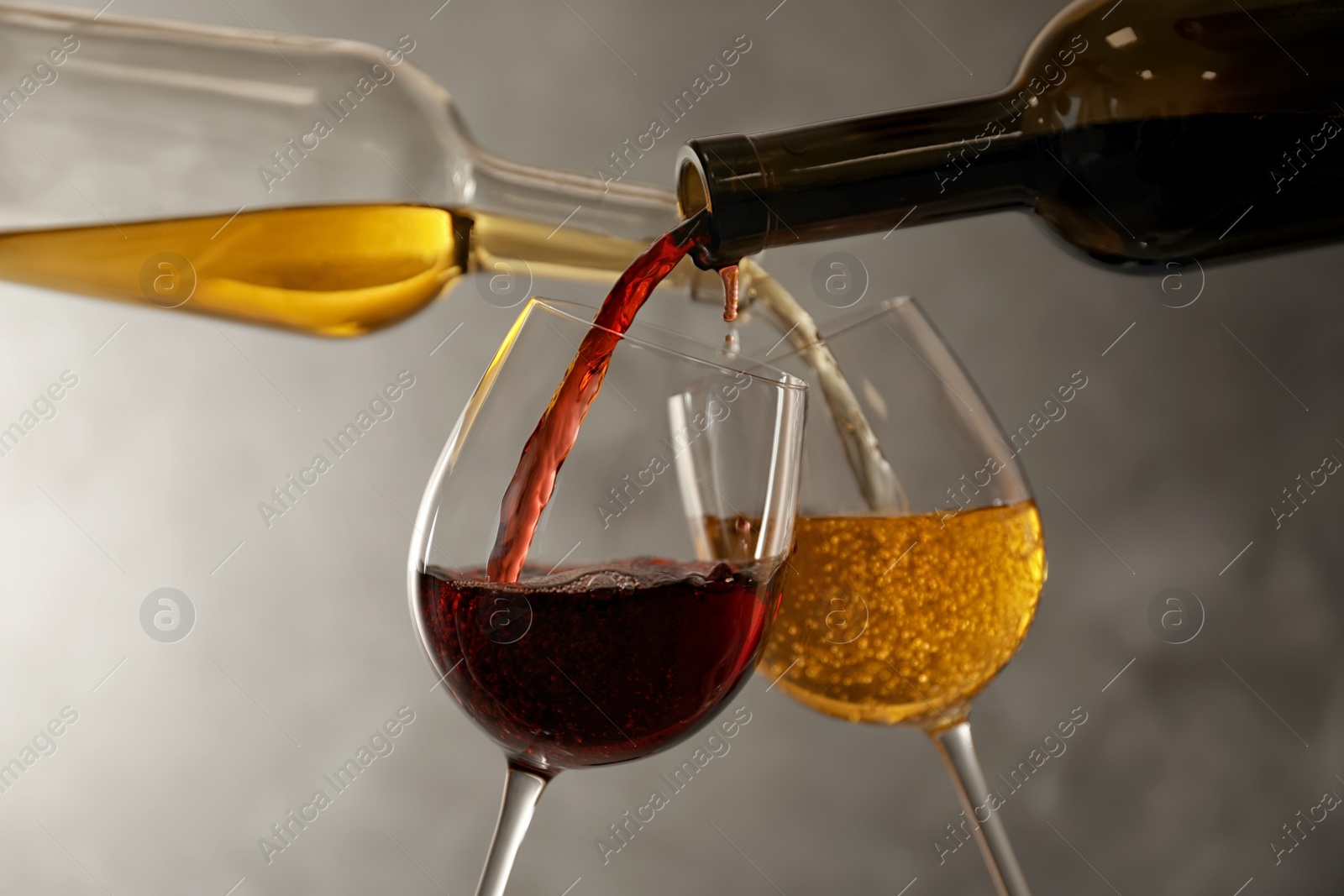 Photo of Pouring different wines from bottles into glasses on dark background