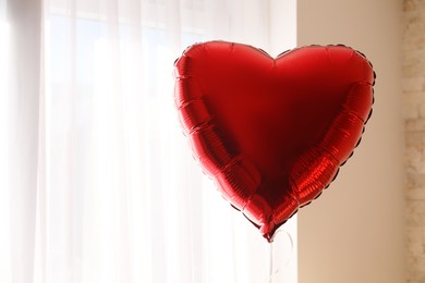 Red heart shaped balloon indoors, space for text