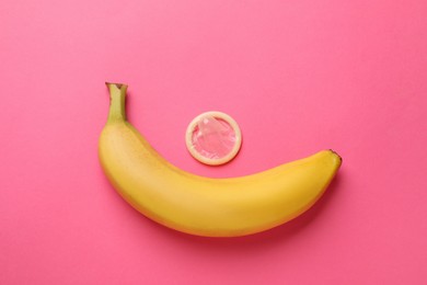 Photo of Banana and condom on pink background, flat lay. Safe sex concept