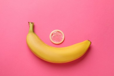 Banana and condom on pink background, flat lay. Safe sex concept