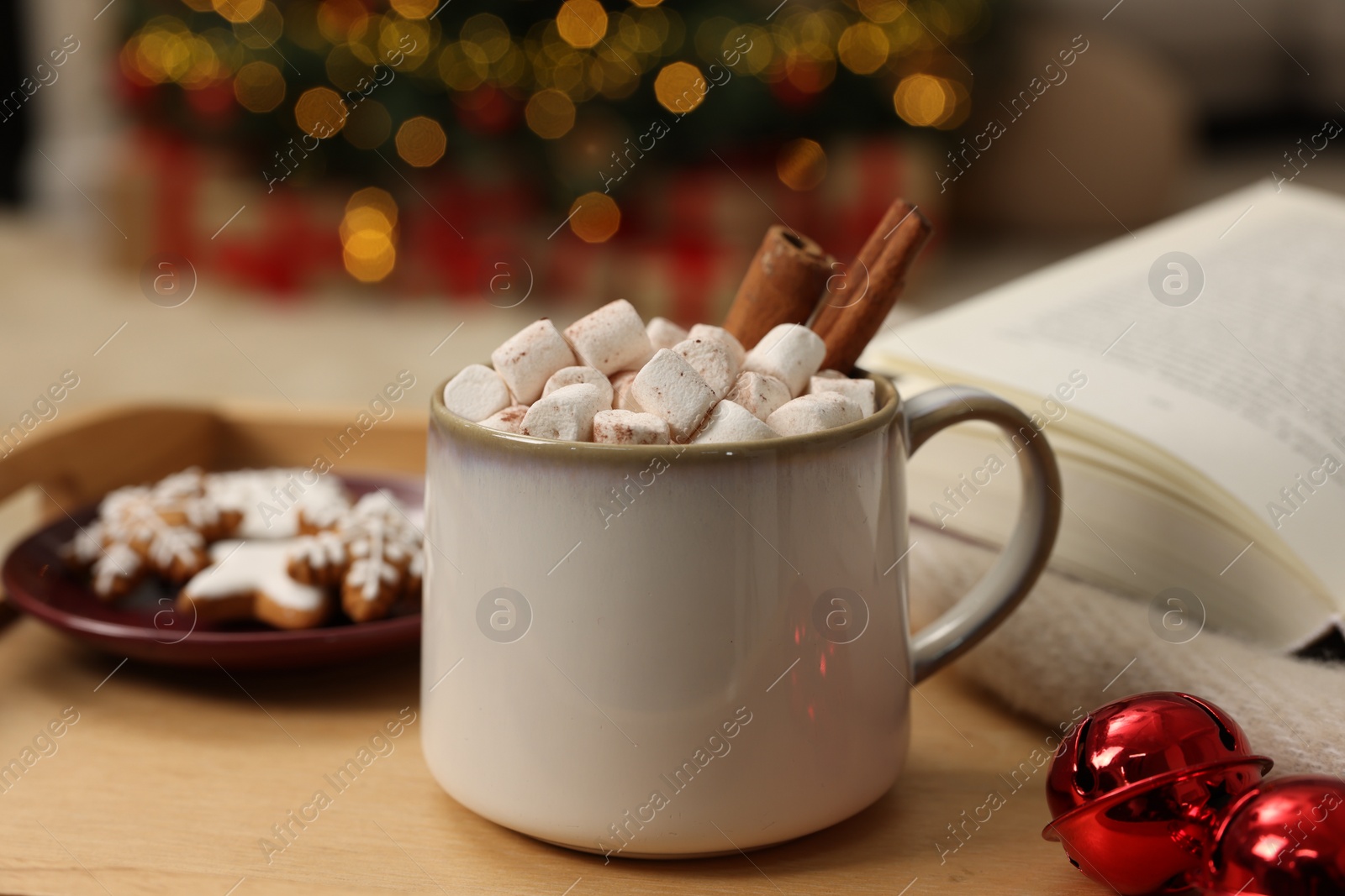 Photo of Christmas cocoa with marshmallows and cinnamon sticks in grey cup on wooden tray indoors, closeup