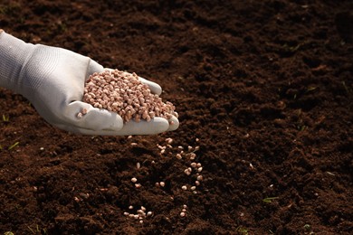 Photo of Man fertilizing soil, closeup. Space for text