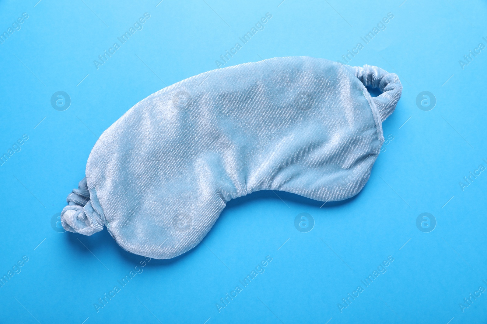 Photo of Soft sleep mask on light blue background, top view