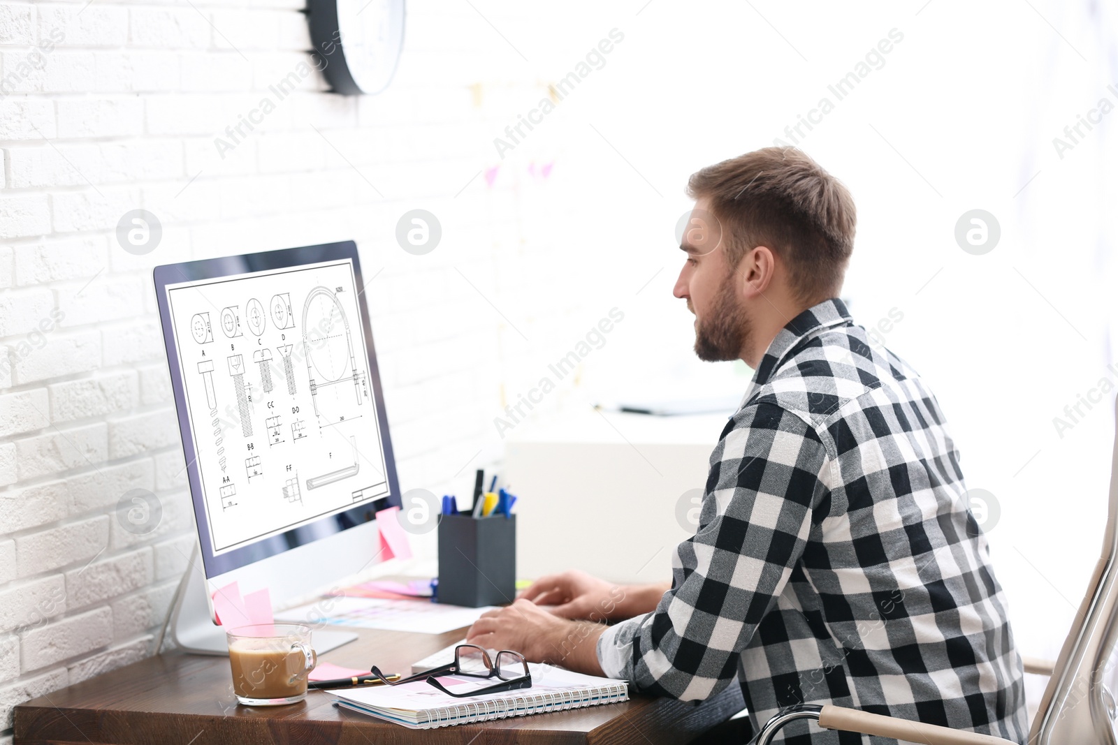 Image of Male engineer working with technical drawing on computer indoors