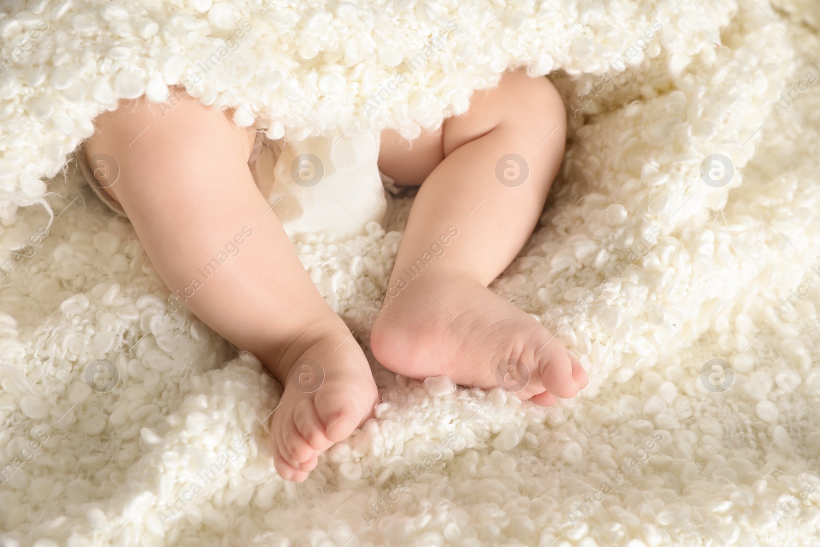 Photo of Little baby with cute feet on soft blanket, above view