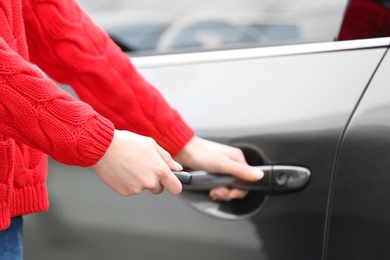 Closeup view of woman opening car door with remote key