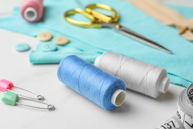 Photo of Threads and other sewing supplies on white marble table, closeup