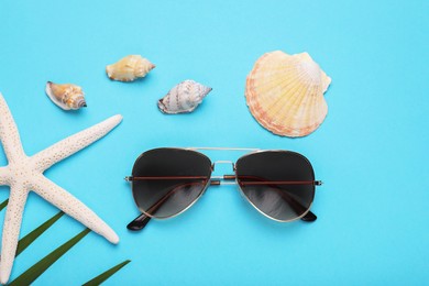 Photo of Stylish sunglasses, starfish and seashells on light blue background, flat lay