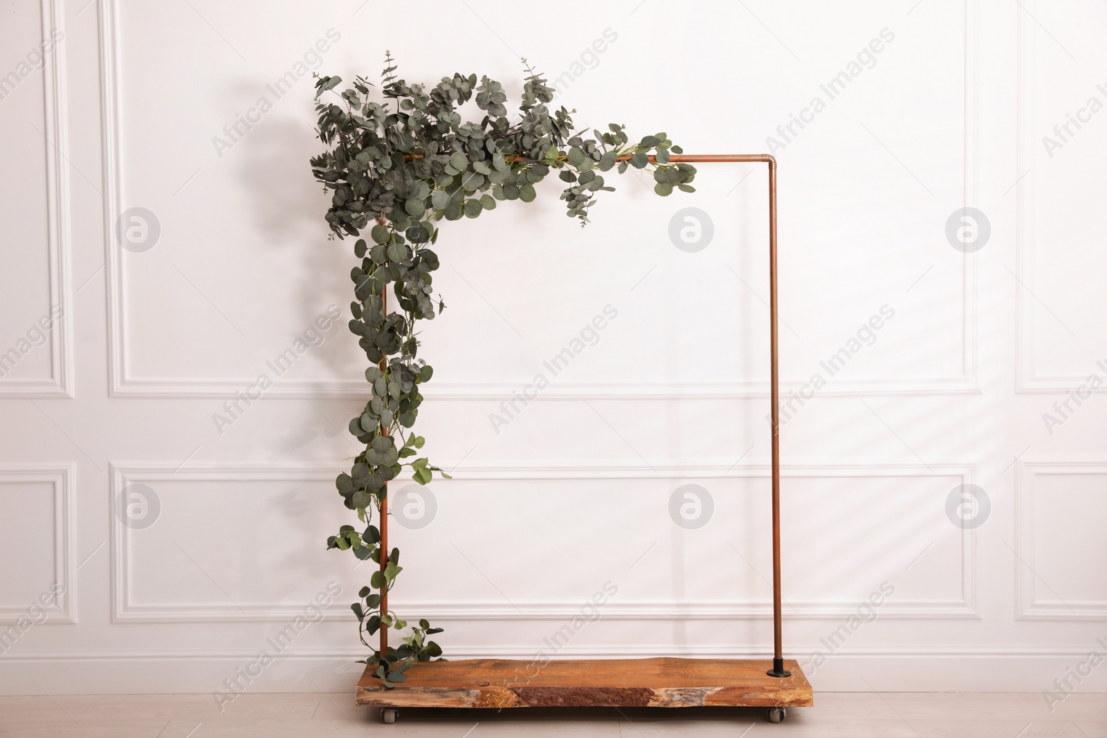 Photo of Stylish photo zone with wooden frame and green leaves indoors