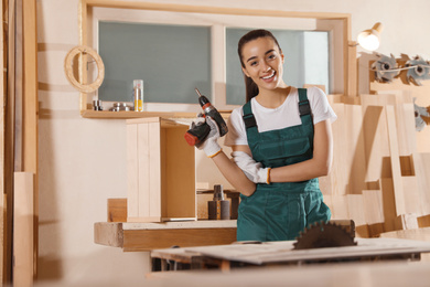Photo of Professional carpenter in uniform with drill near workbench