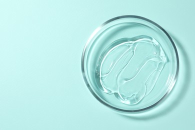 Photo of Petri dish with liquid on turquoise background, top view. Space for text