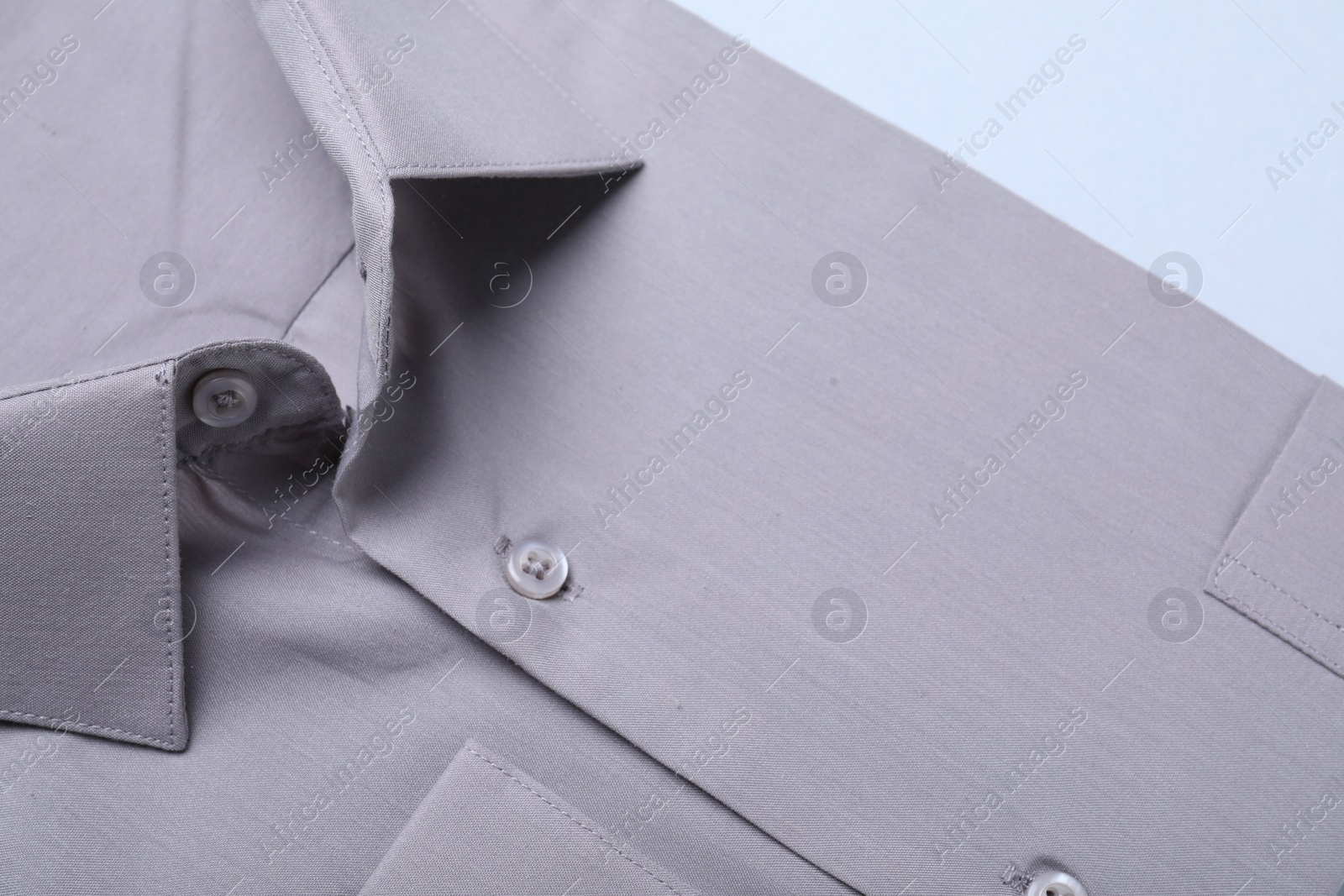 Photo of Stylish grey shirt on white background, closeup. Dry-cleaning service