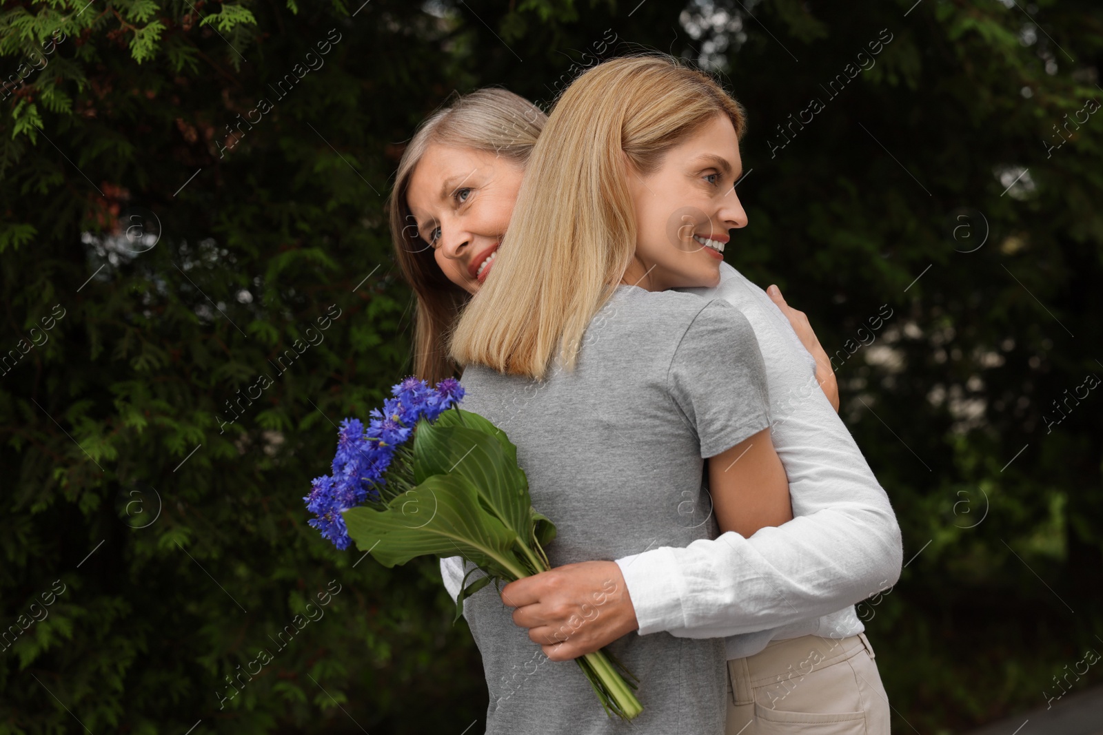 Photo of Happy mature mother and her daughter hugging outdoors