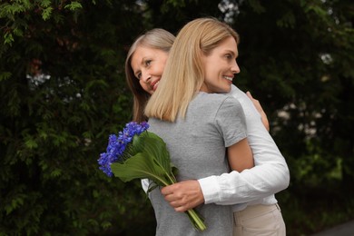 Happy mature mother and her daughter hugging outdoors