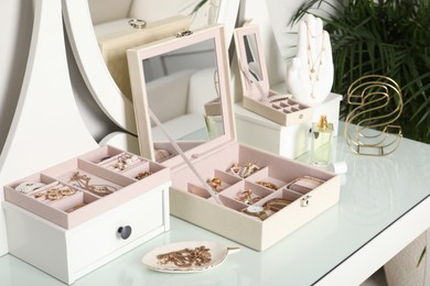 Elegant jewelry boxes with beautiful bijouterie, luxury perfume and stylish accessories on dressing table