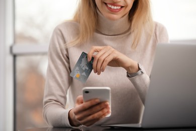 Photo of Woman with credit card using laptop and smartphone for online shopping, closeup