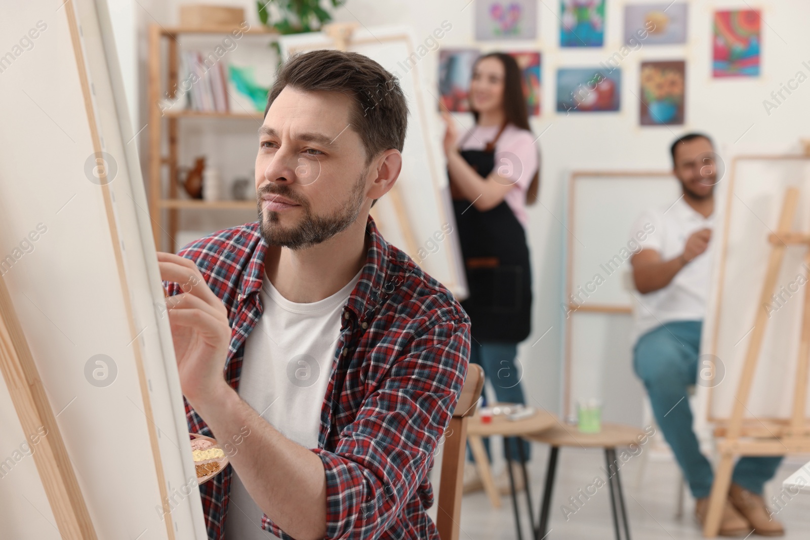 Photo of Group of students attending painting class in studio. Creative hobby