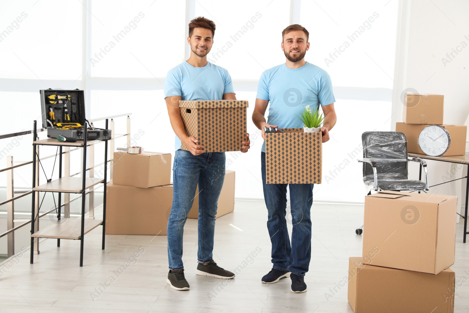 Photo of Professional workers with cardboard boxes in office. Moving service