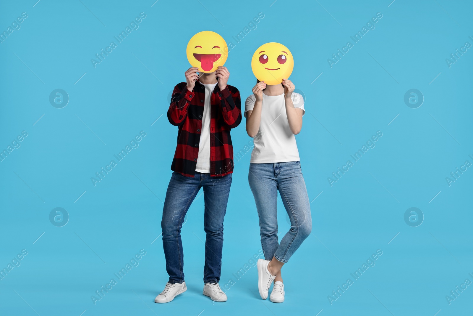 Photo of People covering faces with emoticons on light blue background
