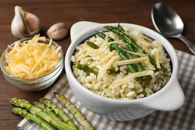 Photo of Delicious risotto with asparagus served on wooden table, closeup