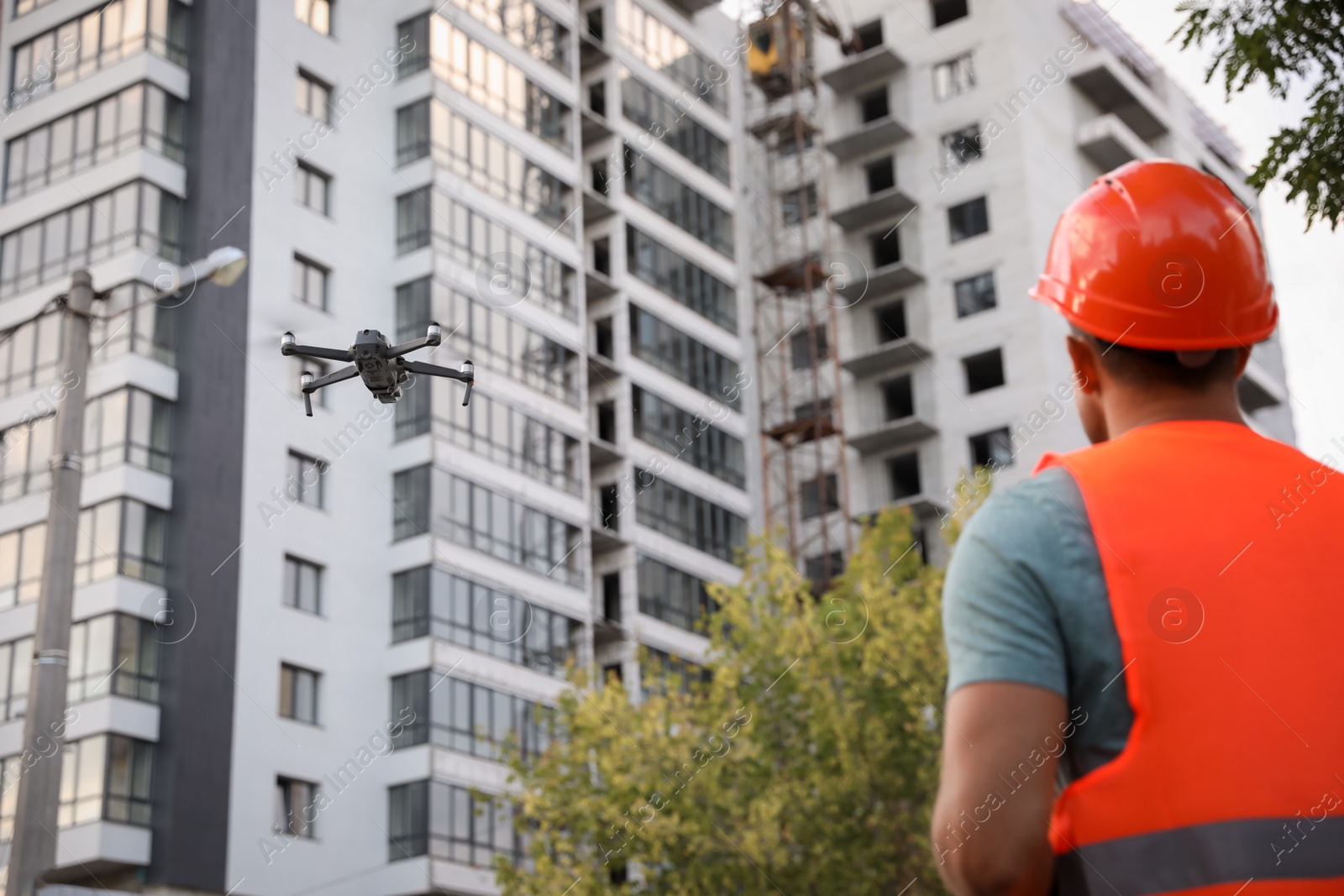 Photo of Builder operating drone with remote control at construction site. Aerial photography