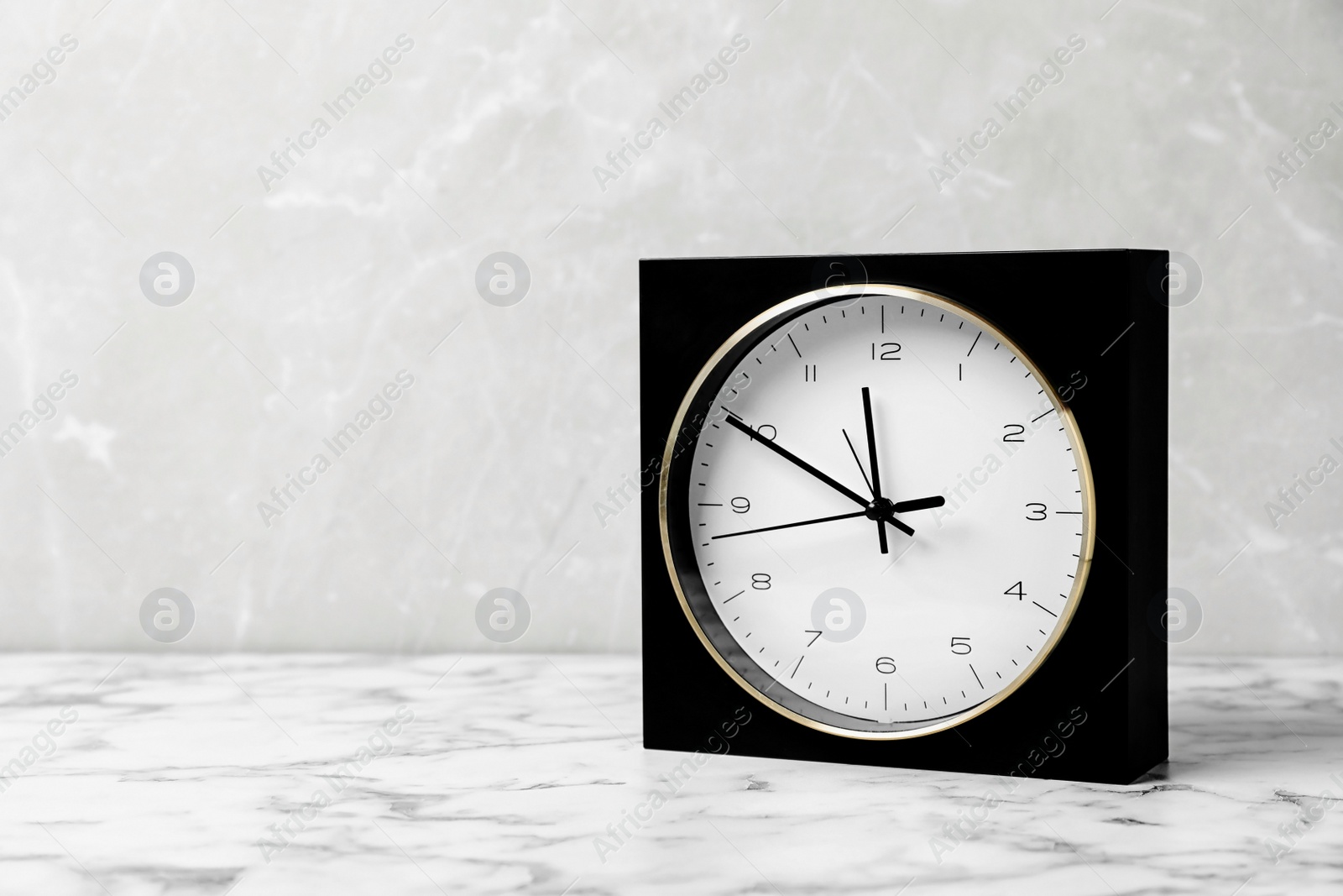 Photo of Modern clock on marble table. Time management