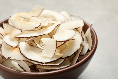 Photo of Tasty coconut chips in ceramic bowl, closeup