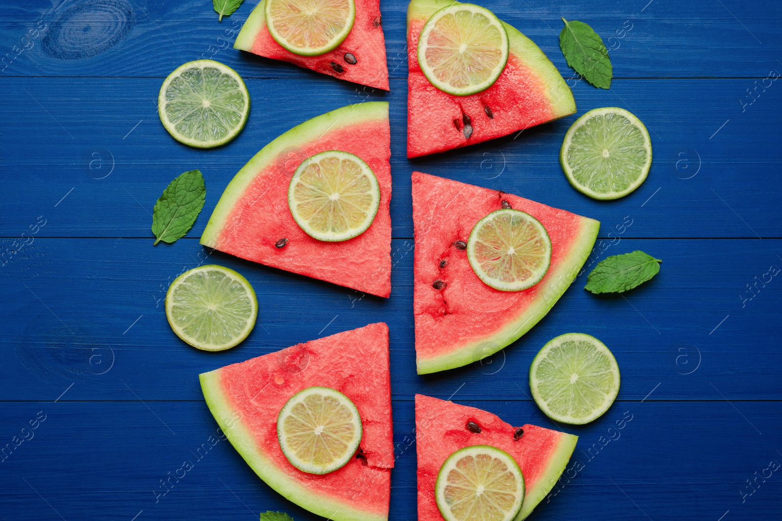 Photo of Tasty sliced watermelon and lime on blue wooden table, flat lay