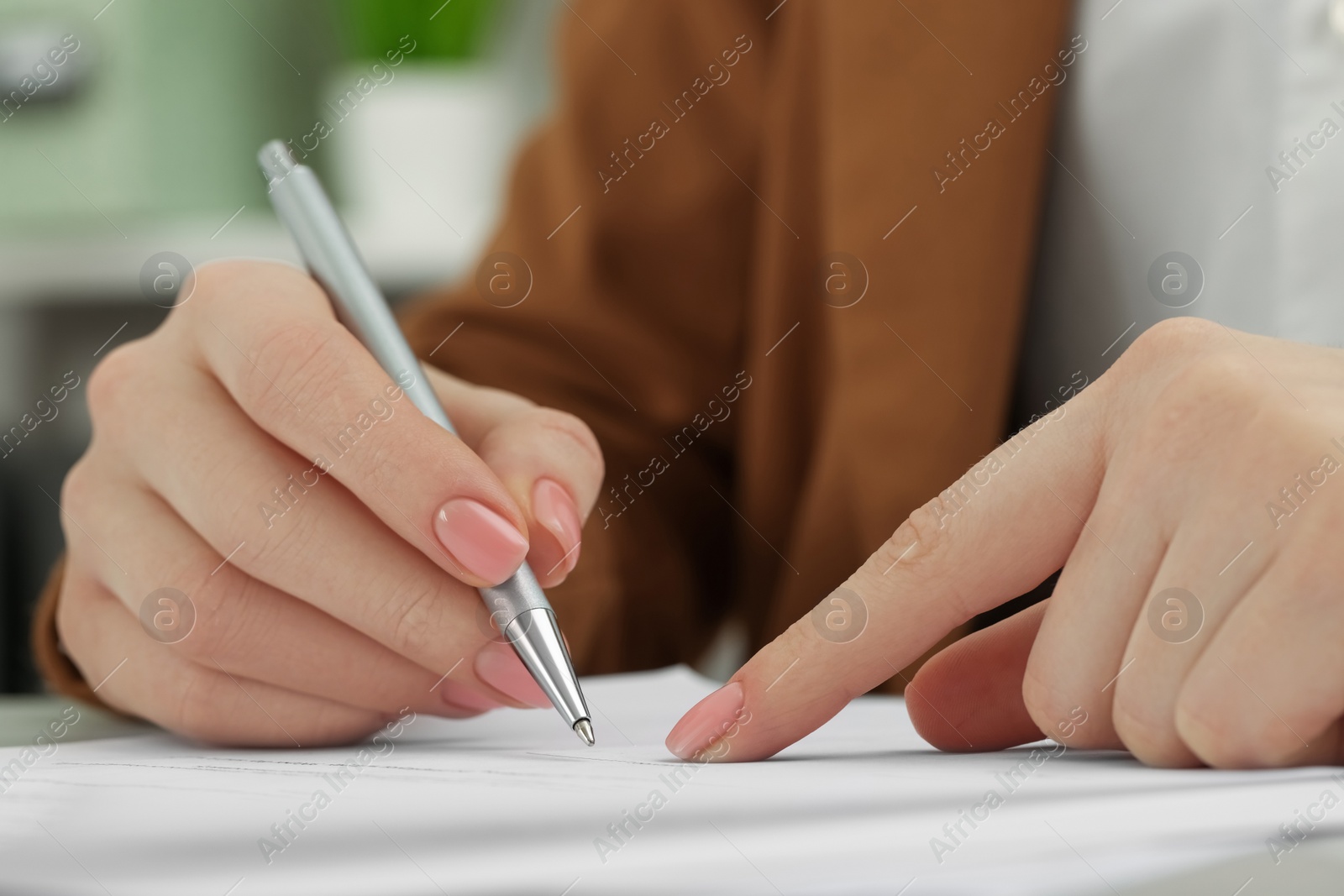 Photo of Woman signing document at table, closeup view