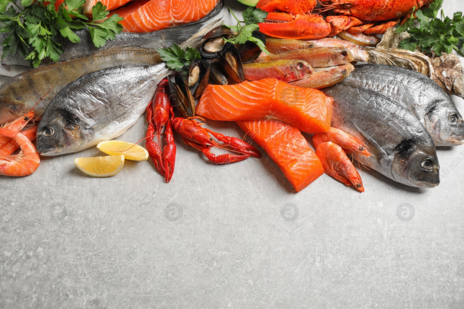 Photo of Fresh raw fish and different seafood on light grey table. Space for text