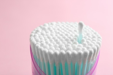 Plastic container with cotton swabs on color background, closeup