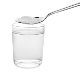 Spoon with baking soda over glass of water on white background