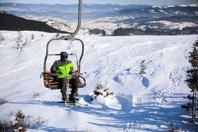 Photo of Man using chairlift at mountain ski resort, space for text. Winter vacation