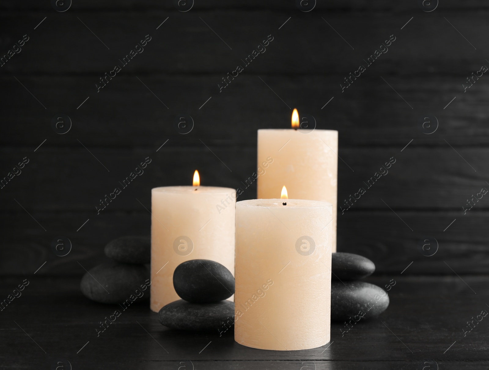 Photo of Burning candles and spa stones on table. Space for text