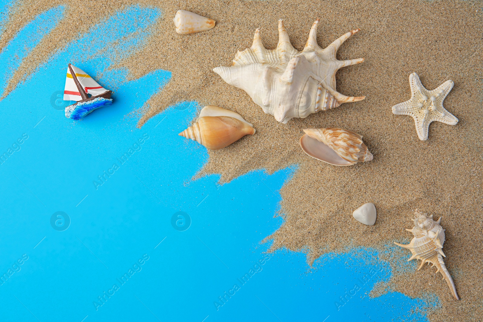 Photo of Flat lay composition with beautiful starfishes and sand on blue background. Space for text