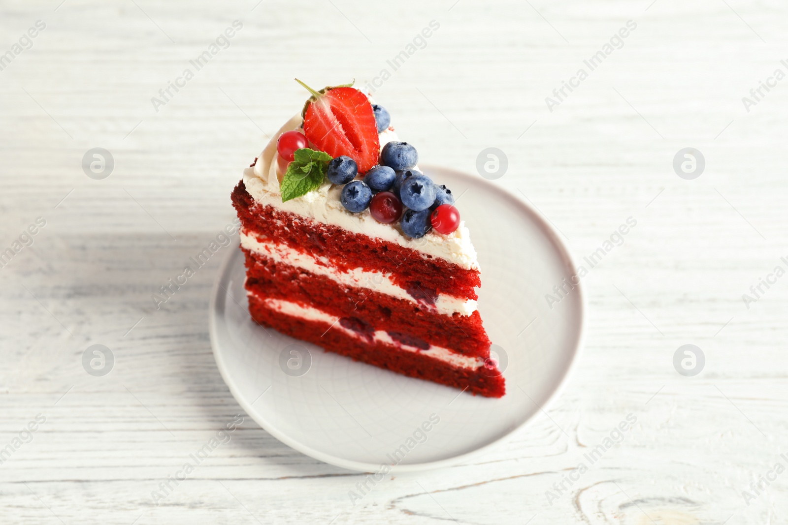 Photo of Plate with piece of delicious homemade red velvet cake on wooden table