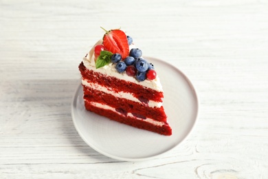 Plate with piece of delicious homemade red velvet cake on wooden table