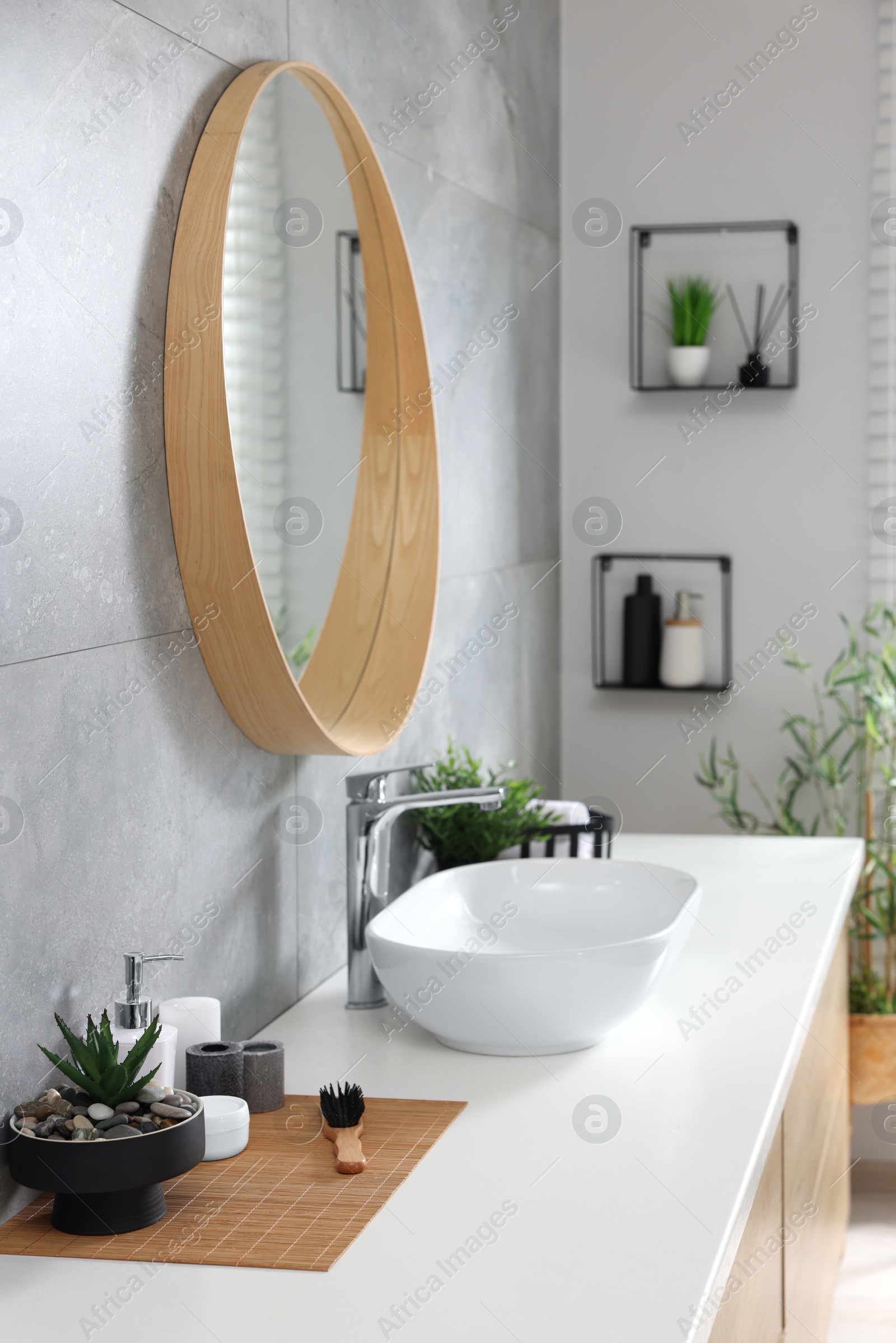 Photo of Potted artificial plants and toiletries near sink on bathroom vanity