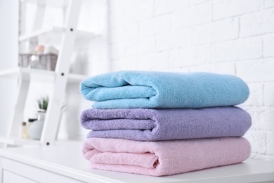 Photo of Stack of fresh towels on table in bathroom. Space for text