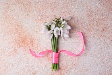 Bouquet of beautiful snowdrops on color textured background, top view