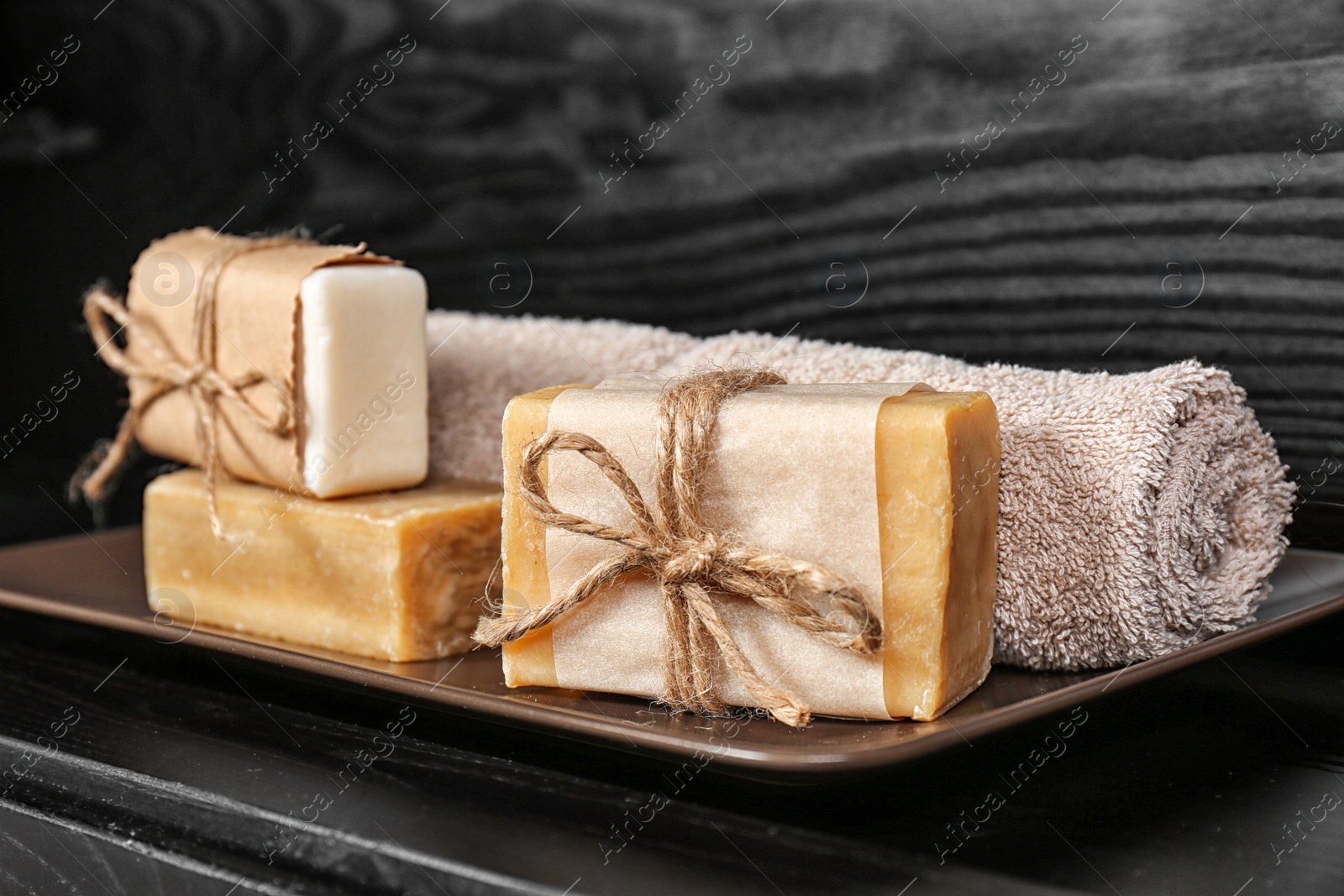 Photo of Plate with soap bars and towel on table