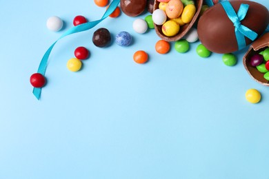 Photo of Composition with tasty chocolate eggs and different candies on light blue background, above view. Space for text