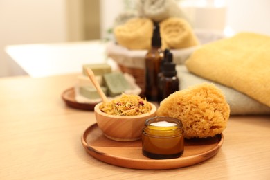 Photo of Loofah, dry flowers and jar with cream on wooden table indoors, space for text. Spa time