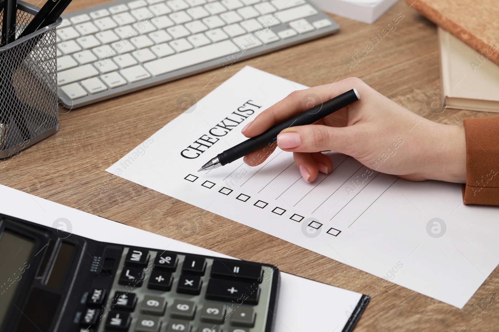 Photo of Woman filling Checklist at wooden table, closeup