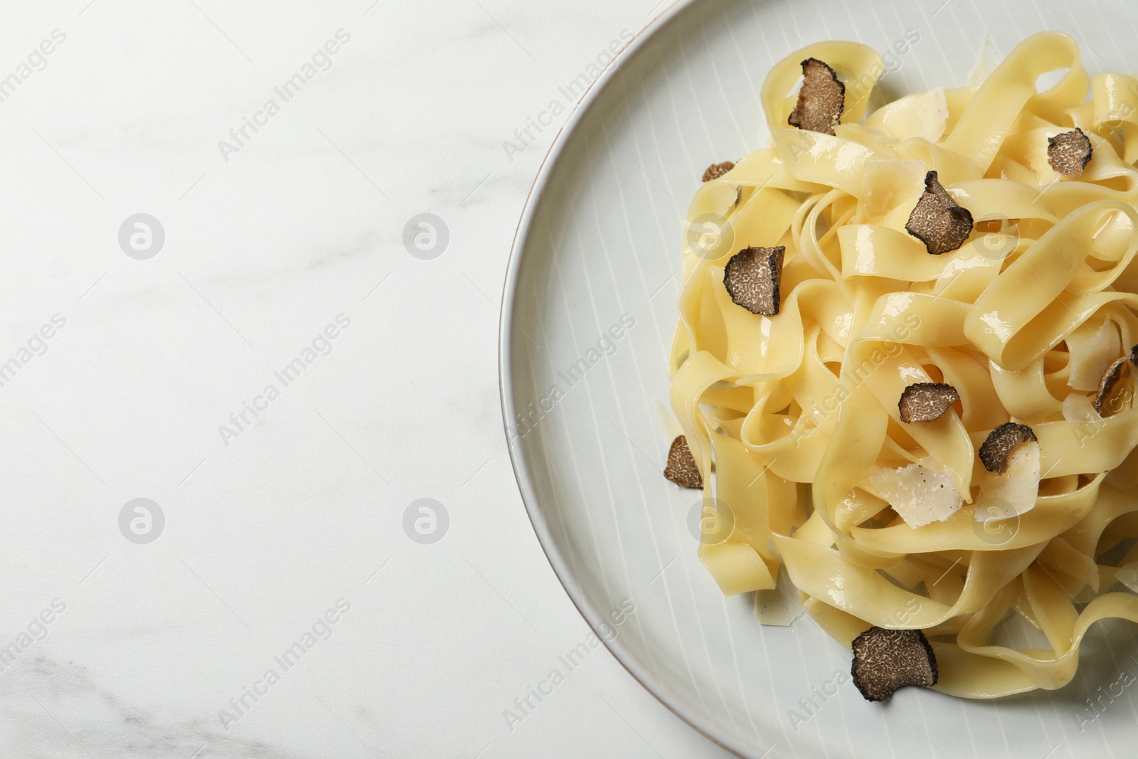 Photo of Delicious pasta with truffle slices on white table, top view. Space for text