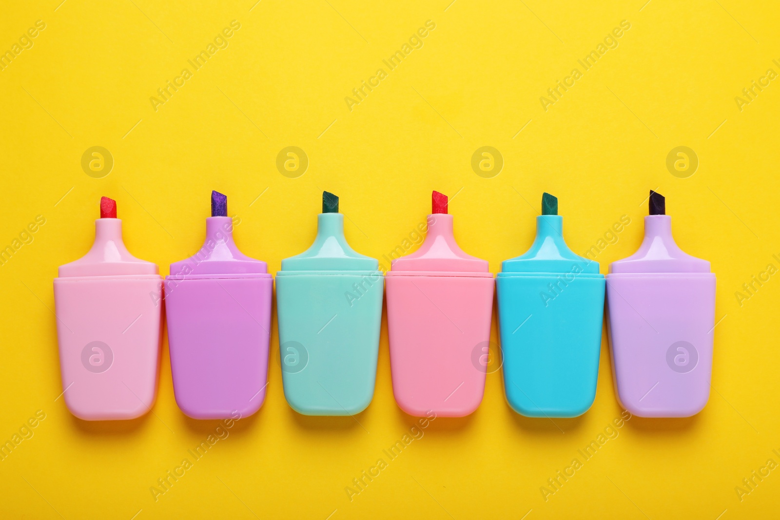 Photo of Many colorful markers on yellow background, flat lay