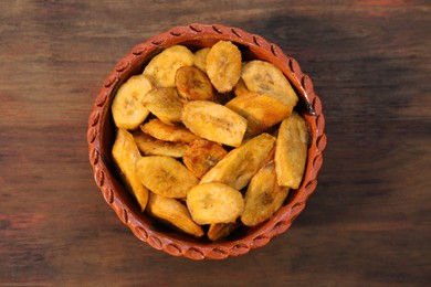 Photo of Tasty deep fried banana slices on wooden table, top view