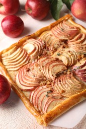 Photo of Tasty apple pie with nuts and fresh fruits on beige textured table, closeup