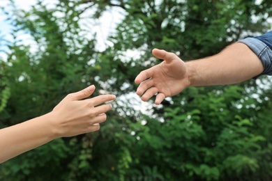 Photo of Man and woman giving each other hands outdoors. Concept of support and help